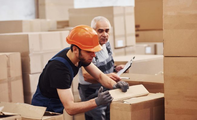 Young and senior storage workers in uniform works together in the warehouse