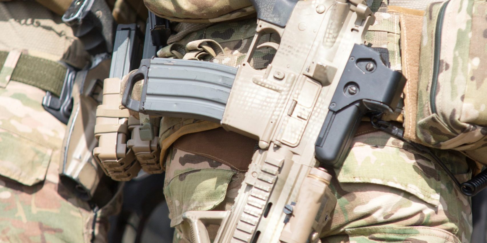 Soldiers in US Army Special Forces uniform, close up on rifle