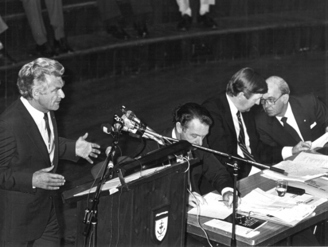 Prime Minister Bob Hawke speaking at the Labor Council of NSW Annual General Meeting, 1984, at the Sydney Town Hall.  On the stage (seated) are from left to right, John MacBean (Assistant Secretary), Barrie Unsworth (Secretary), and Jim Gibson (President).  Photo: from Michael Easson papers, Noel Butlin Archives, Menzies Library, Australian National University.  (Photo not published with article). Prime Minister Bob Hawke speaking at the Labor Council of NSW Annual General Meeting, 1984, at the Sydney Town Hall. On the stage (seated) are from left to right, John MacBean (Assistant Secretary), Barrie Unsworth (Secretary), and Jim Gibson (President). Photo: from Michael Easson papers, Noel Butlin Archives, Menzies Library, Australian National University. (Photo not published with article).